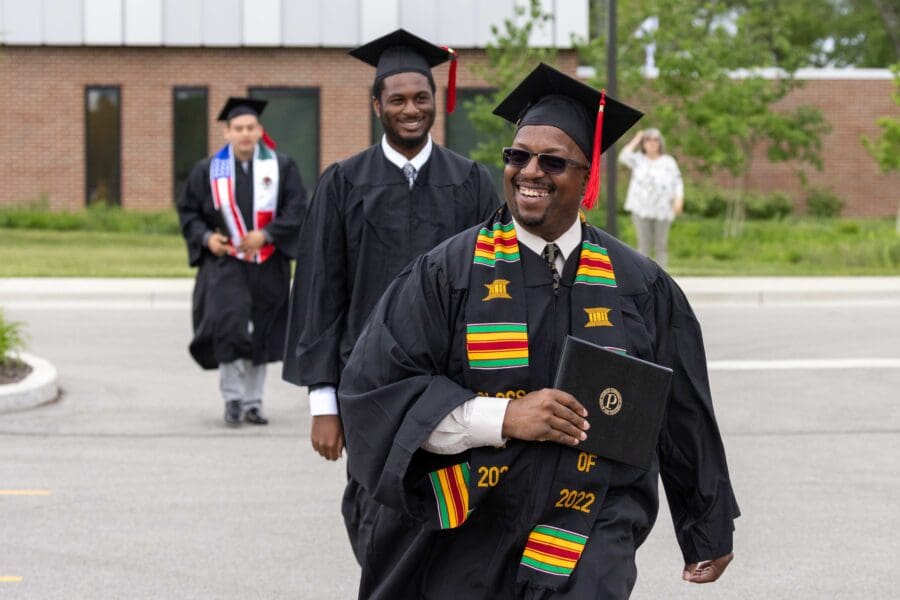 Smiling graduates walking away from commencement