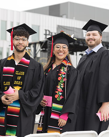 Three students stand together during spring commencement