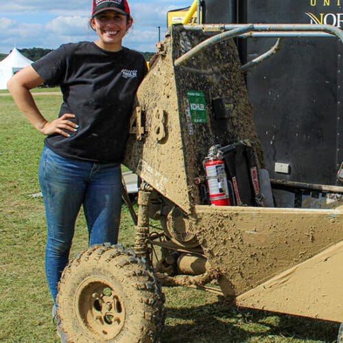 Mia Flory leans against the outside of a race car.