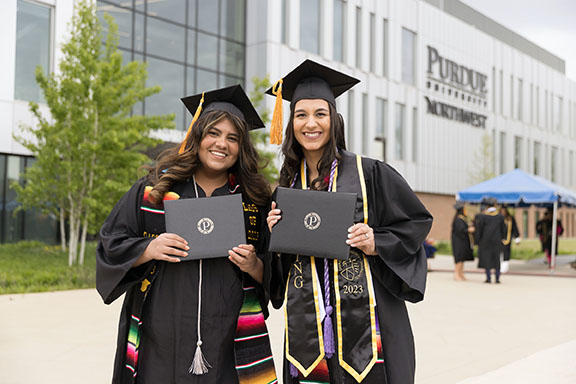 PNW graduates pose with their diplomas outside the Nils K. Nelson Bioscience Innovation Building.