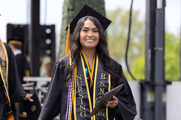 A PNW graduate marches from stage with her degree
