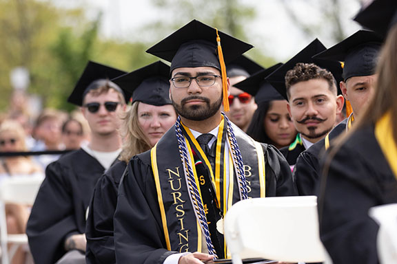 A PNW student with recognition cords sits at commencement