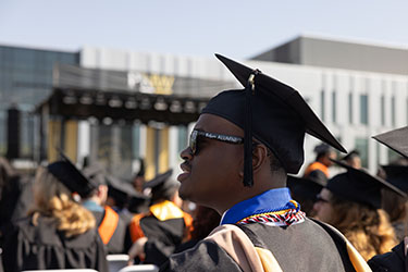 Terrell Sucre stands outside in commencement regalia