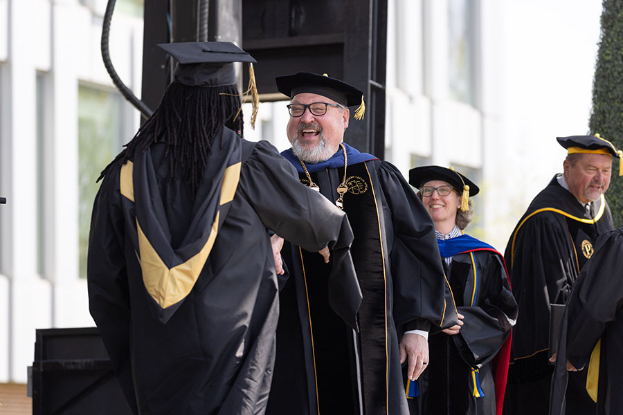 PNW Chancellor Kenneth C. Holford shakes a graduate's hand.