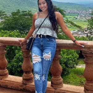 PNW student Fatima Chavez leans against a stone railing in front of a scenic view