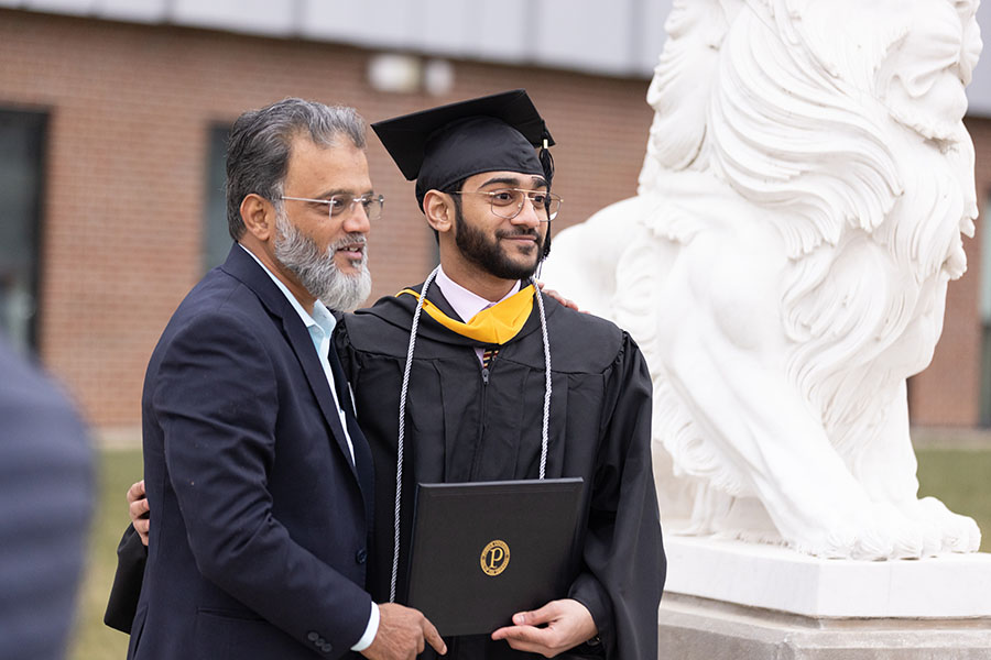 A graduate poses with a family member after commencement