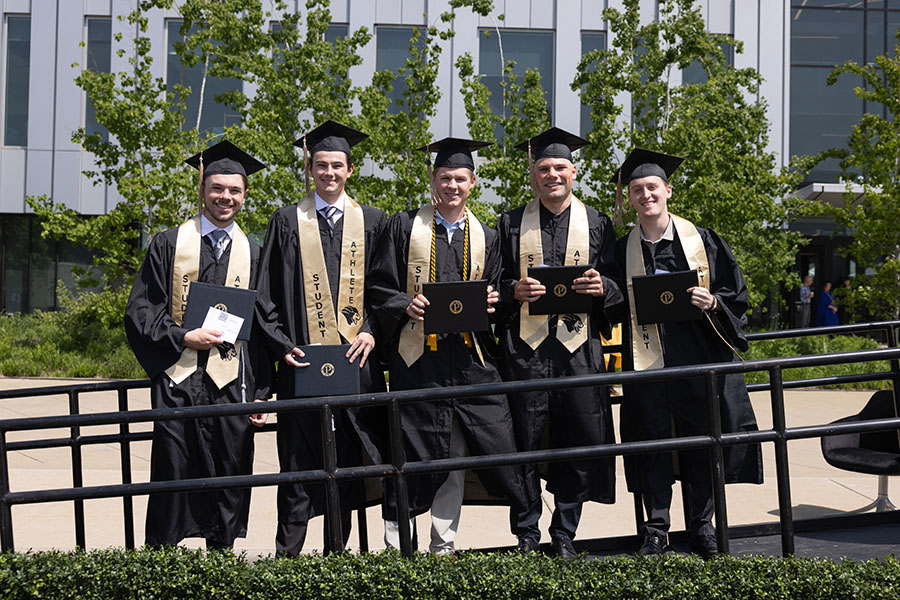 Five student athletes pose with their degrees
