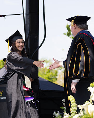 Graduate reaches out to shake Chancellor Holford's hand during commencement