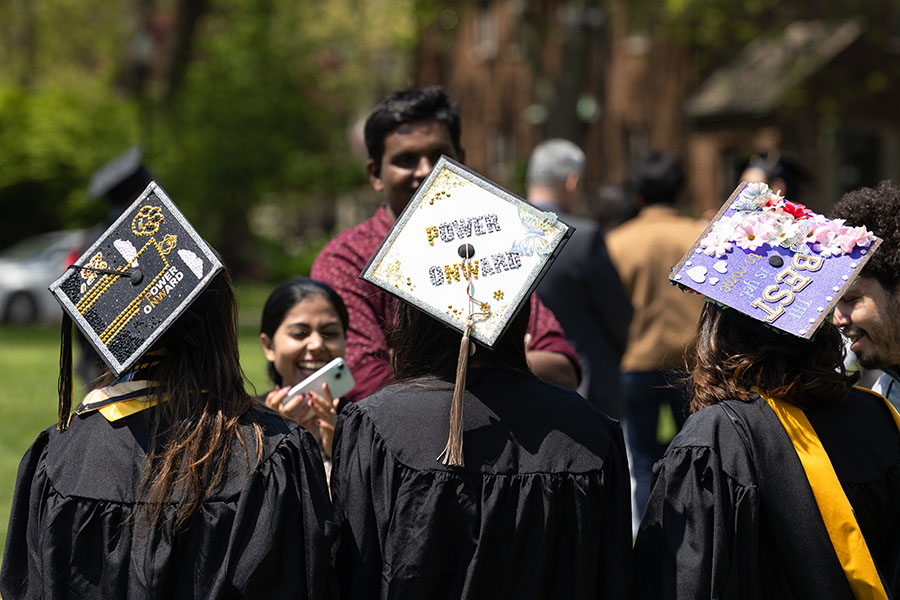 Three graduates with decorated caps pose together.