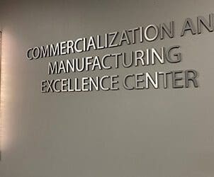 A wall sign that reads "Commercialization and Manufacturing Excellence Center"