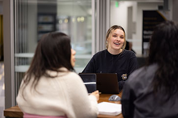 Students sit at a table and work together