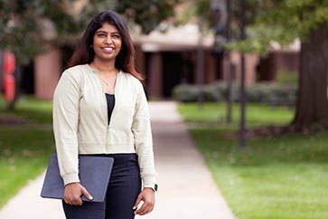 A PNW student stands outdoors on campus