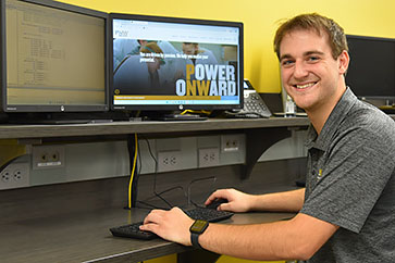 A PNW computer science major in front of a computer showing the PNW website homepage