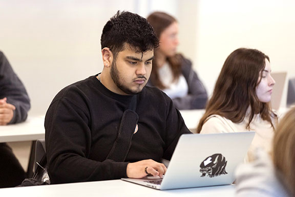 A PNW student on his laptop in the classroom