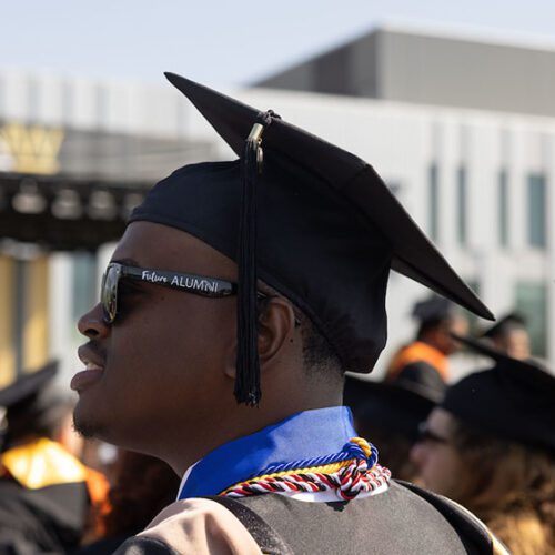 Terrell Sucre stands outside in commencement regalia