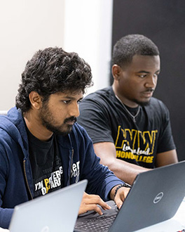 Two students both working on their laptops
