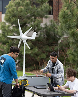 Three students working on an assignment at a picnic table