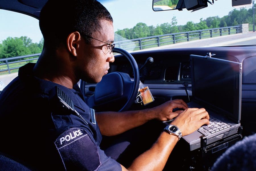 First responder working on computer in car