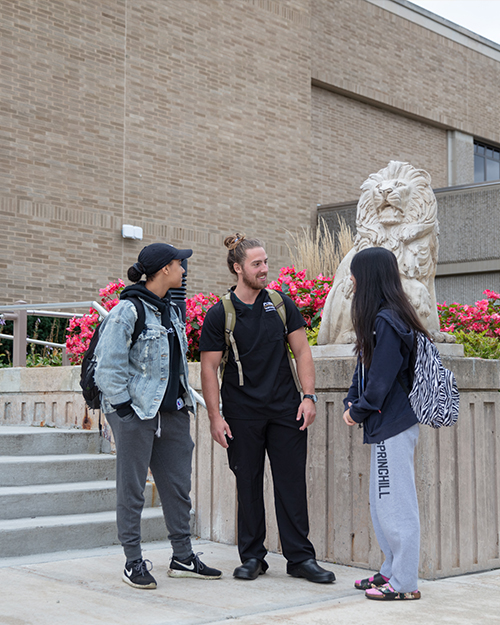 Students stand near a PNW lion sculpture