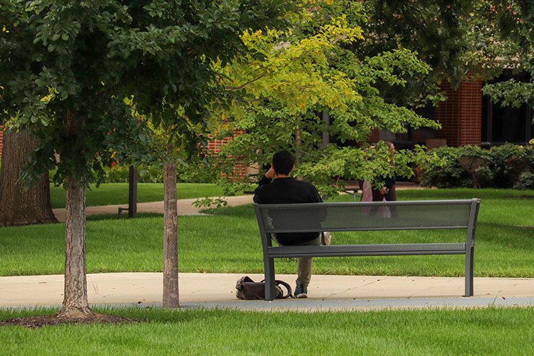 A student sits on a bench outside on the PNW Hammond Campus