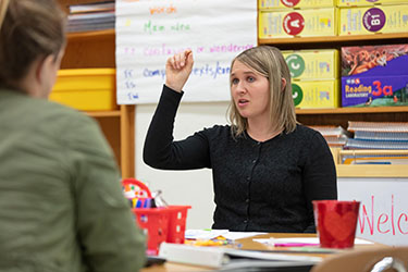 A PNW students sits in a classroom surrounded by education posters.