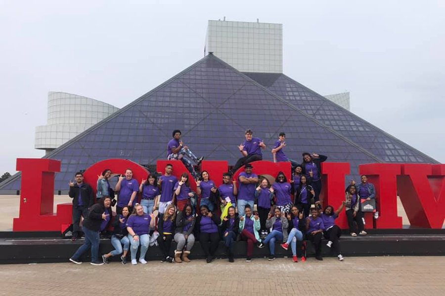 Students posed on and around a sign outside of the Rock and Roll Hall of Fame