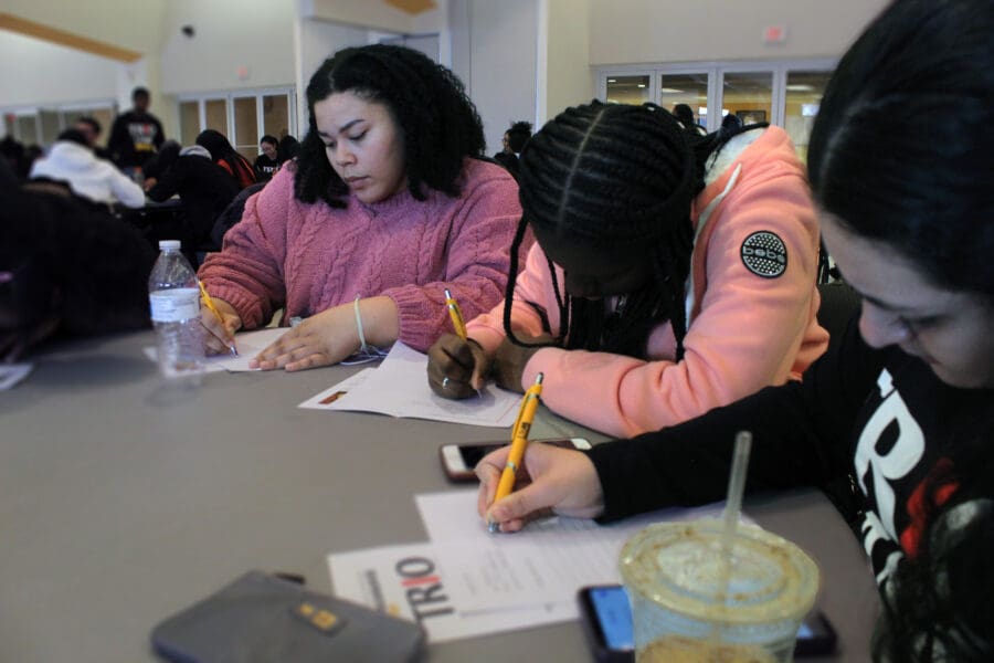 Three Upward Bound students participating in a writing activity for TRIO Day on the University of Milwaukee Wisconsin campus.