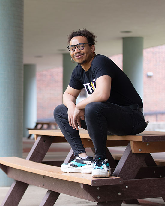 A student wearing a TRIO SSS t-shirt sits on a picnic table