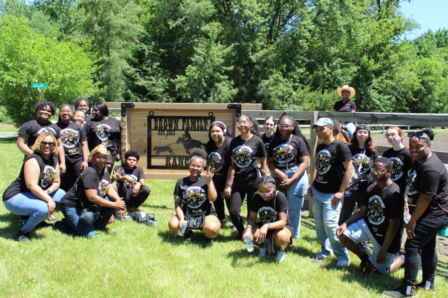 Students standing in front of a "Brown Family Ranch" sign