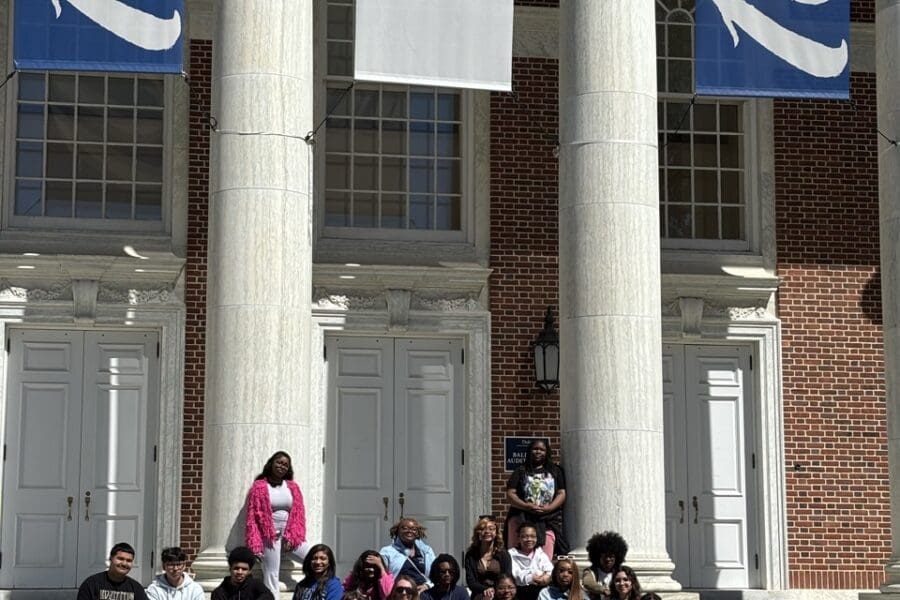 a group of student in front of building with pillars and "Duke 100 years" banners.