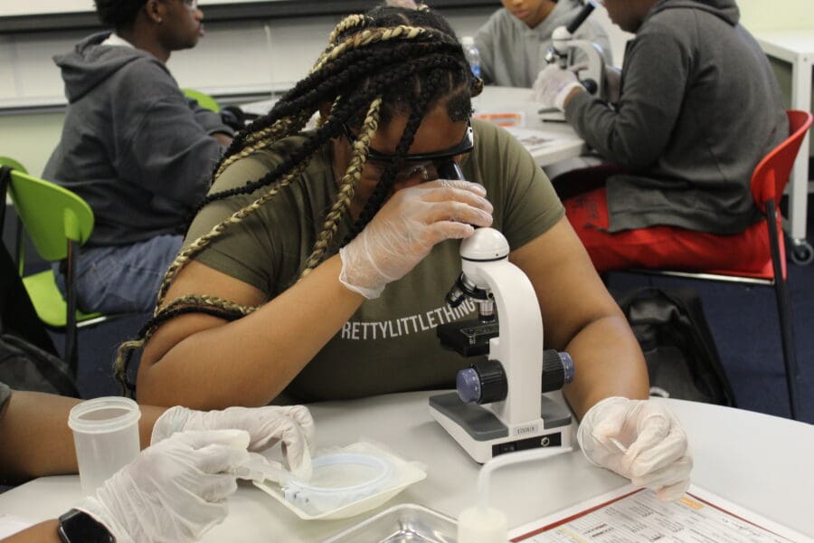 high school girl looking through a microscope