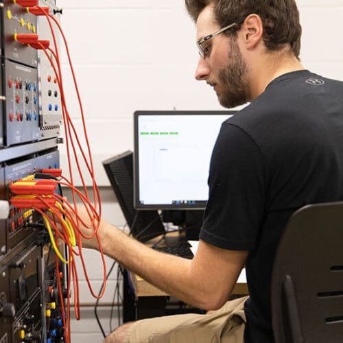 A student plugs wires into a box