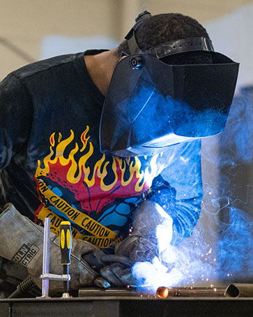 An engineering student welds and item.