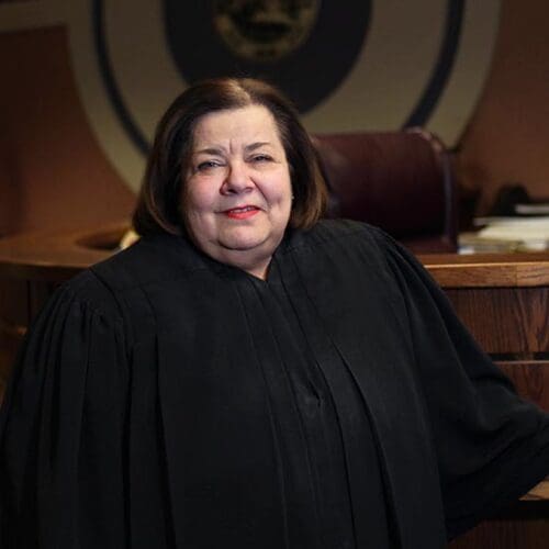 The Honorable Diane Kavadias Schneider poses in judicial robes in a courtroom