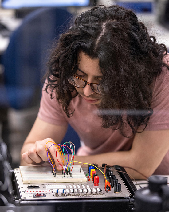 Un estudiante trabaja en una placa de circuito(masculine)