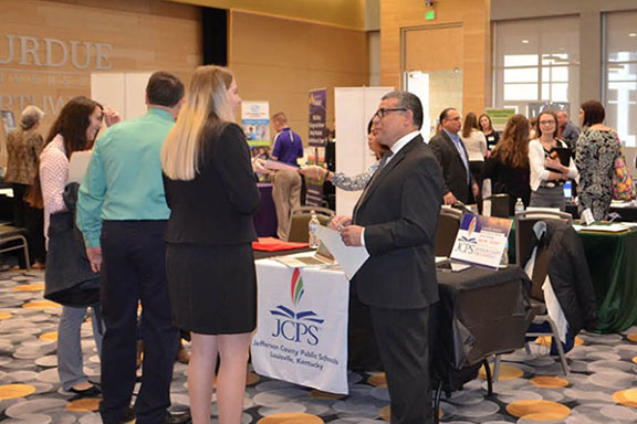 People in dress clothes around tables set up for a PNW career expo.