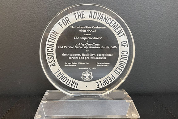 A glass award from the National Association for the Advancement of Colored People. Text: The Indiana State Conference of the NAACP presents The Corporate Award to Ashley Gerodimos and Purdue University Northwest- Westville for their support, flexibility, exceptional service and professionalism.