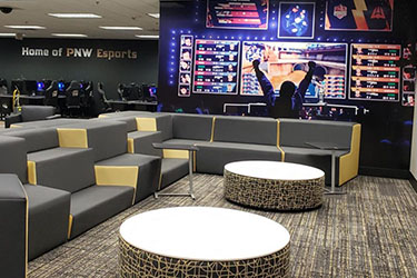 The PNW Esports Arena, complete with a large screen, couches and computer stations.