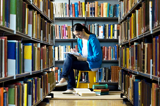 Student surrounded by books in a library