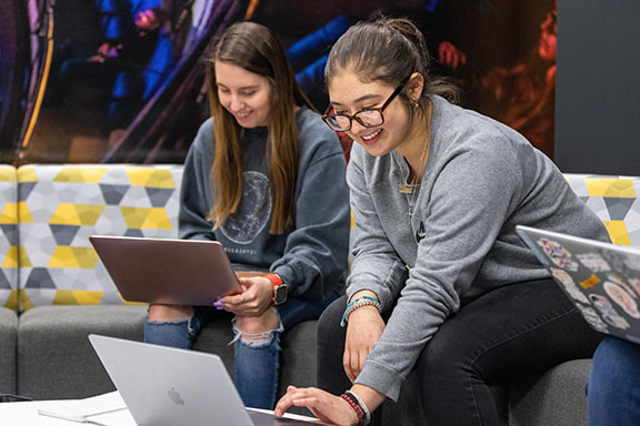 PNW students collaborate on computers in a lounge space