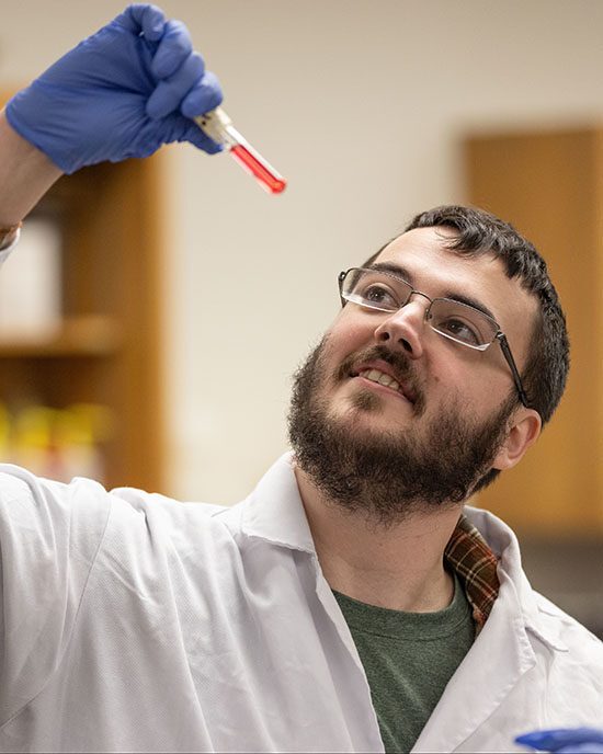 A PNW student looks at a vial in the lab.