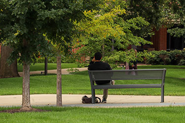 A student sits on a bench outdoors on the PNW Hammond Campus