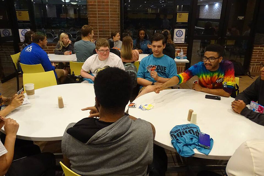Students sitting around a table and holding uno cards