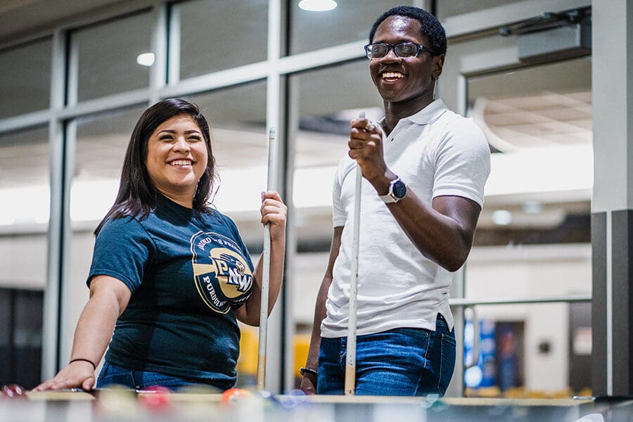 Two students smiling behind a billiards table