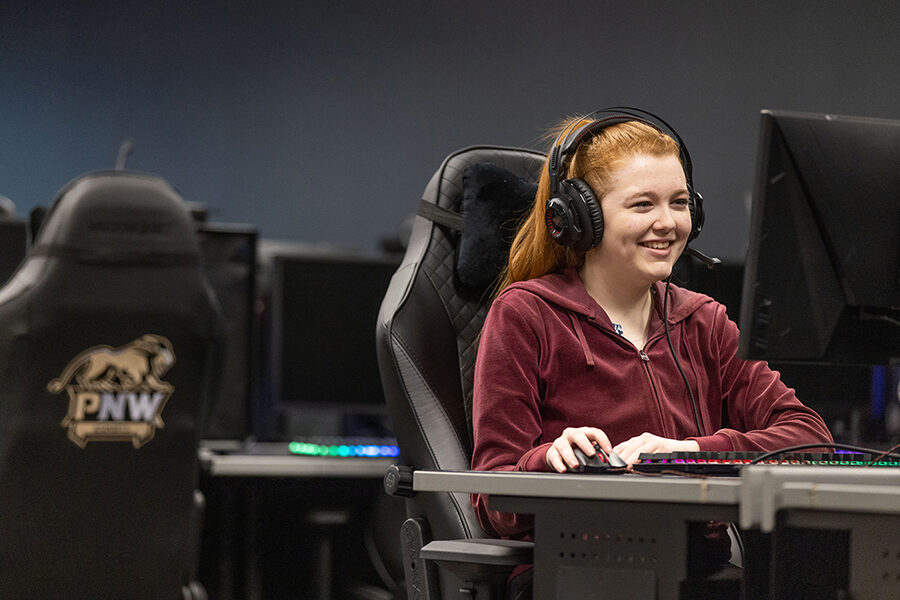 Student smiling at a computer in the Esports room
