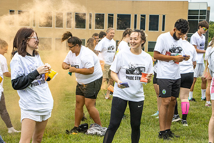 Students hold bags of color powder to throw at each other