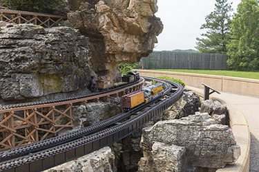 Model train tracks run through carved rock