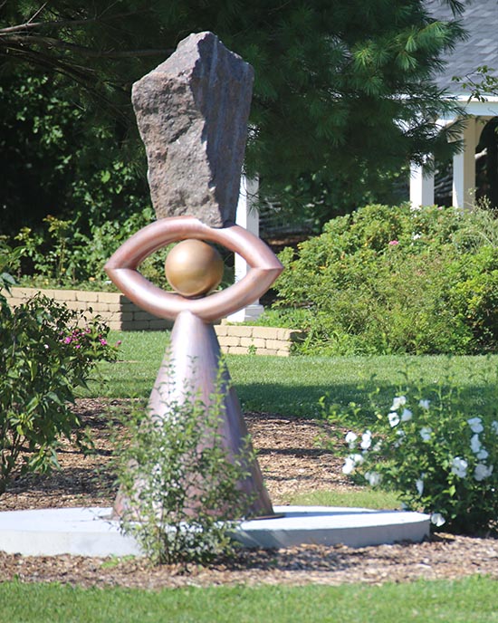 Eye sculpture with bushes and grass in the background at Gabis Arboretum