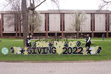 Students stand by a yard decoration that says "PNW Day of Giving 2022"