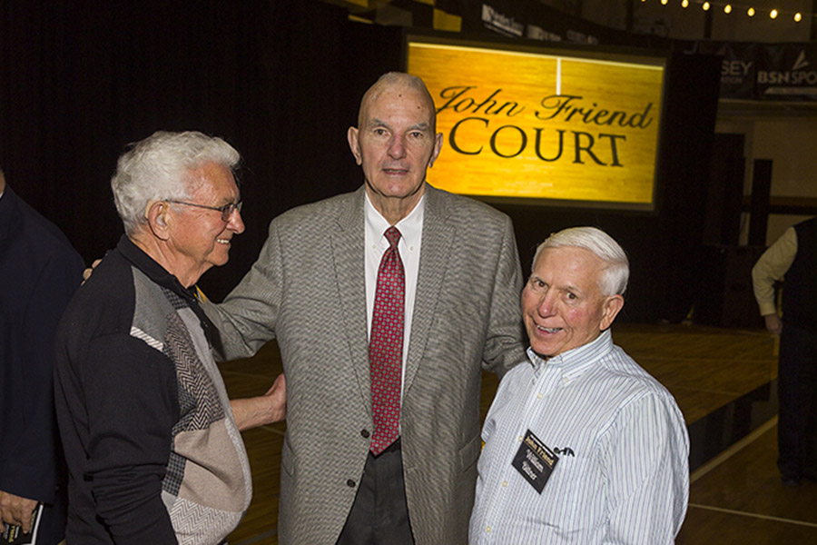 Coach John Friend poses with people in front of a sign reading John Friend Court